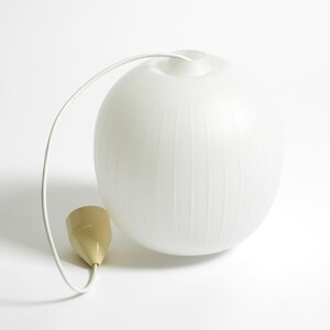 Puede incluir: L&aacute;mpara colgante esf&eacute;rica blanca con ranuras verticales. La l&aacute;mpara tiene un cable blanco y un elemento en forma de cono dorado. El dise&ntilde;o es minimalista y moderno, adecuado para la iluminaci&oacute;n interior.