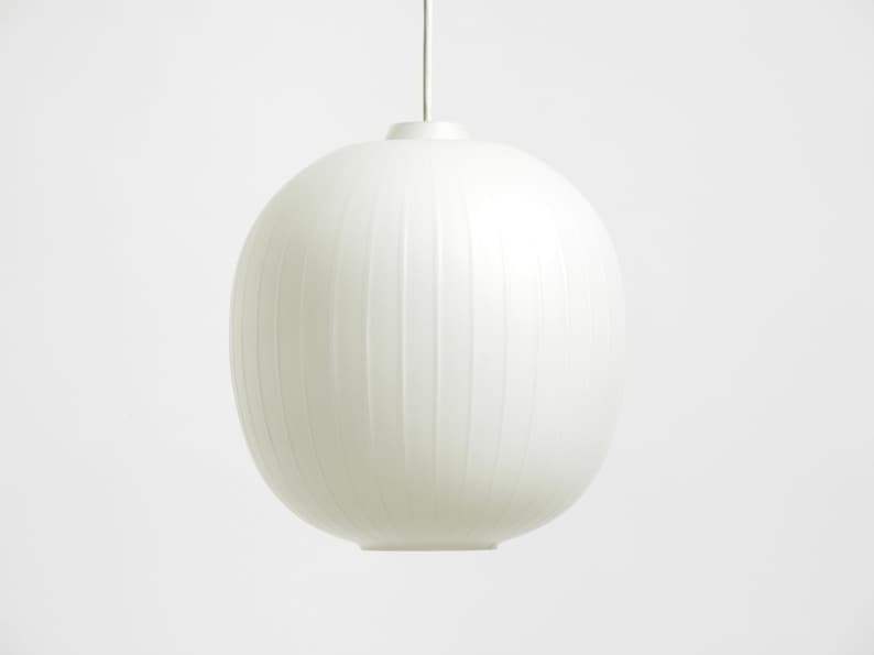 Puede incluir: L&aacute;mpara colgante ovalada blanca con l&iacute;neas verticales texturizadas. Cuelga de un fino cable blanco. El dise&ntilde;o minimalista es adecuado para interiores modernos. Aproximadamente 30 cm de di&aacute;metro.