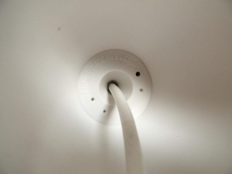May include: White ceiling fixture with a white cord and a white plastic cover with the text "LUXUS MADE IN SWEDEN".