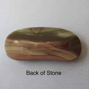 May include: An oval-shaped stone with a polished surface. The stone features a blend of colors, including tan, brown, and reddish-brown hues, with a layered pattern. The text "Back of Stone" is visible.