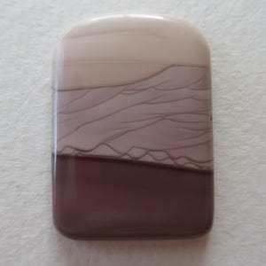 May include: A rectangular, polished stone with rounded corners. The stone features a layered design with shades of beige, mauve, and deep burgundy. The layers have a natural, organic appearance, with subtle veining.