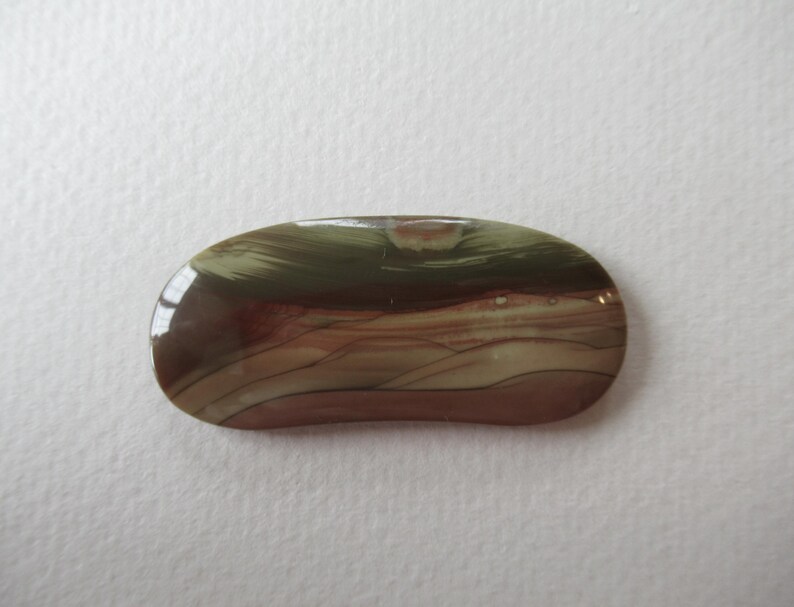 May include: A polished, oval-shaped gemstone with a mix of colors. The stone features bands of brown, tan, and green, creating a natural, earthy pattern. The surface is smooth and reflective, suggesting a high-quality finish.