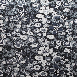 Puede incluir: Una tela negra con un patrón floral blanco y gris. La tela está cubierta de una variedad de flores, incluyendo flores pequeñas y simples y flores más grandes y elaboradas.