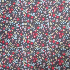 Puede incluir: Una tela gris oscura con un patrón repetitivo de pequeñas flores rojas, azules, amarillas y rosas. La tela tiene una textura sutil.