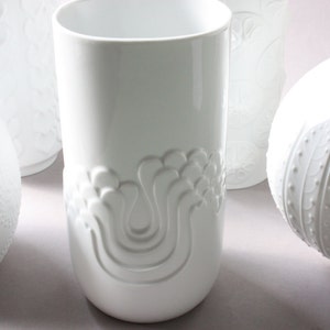 May include: Four white ceramic vases with embossed floral designs. The vases are all different shapes and sizes.