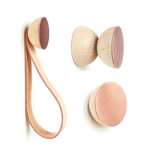 Op de afbeelding: Drie houten wandhaken met een koperen afwerking. Eén haak heeft een leren riem.