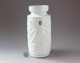 May include: White ceramic vase with an embossed floral design. The vase has a round body and a slightly flared lip.