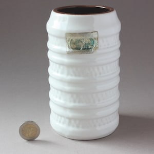 Könnte beinhalten: Weiße Keramikvase mit braunem Rand und einem strukturierten Design. Die Vase hat einen Aufkleber an der Seite mit dem Text "525".