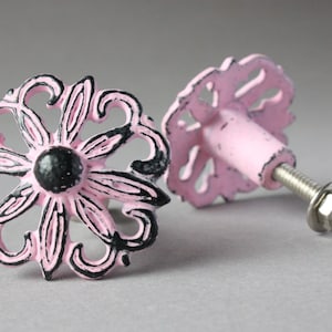Könnte beinhalten: Zwei rosafarbene und schwarze Metall-Schubladengriffe mit floralem Design. Die Griffe haben eine Schraube auf der Rückseite zum Befestigen an einer Schublade.