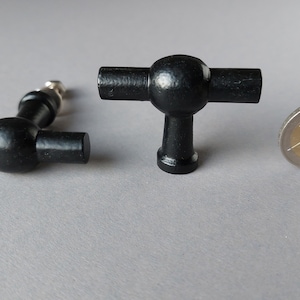 Peut inclure: Deux boutons de porte en T noirs avec un centre rond. Les boutons ont à peu près la taille d'une pièce d'un euro.