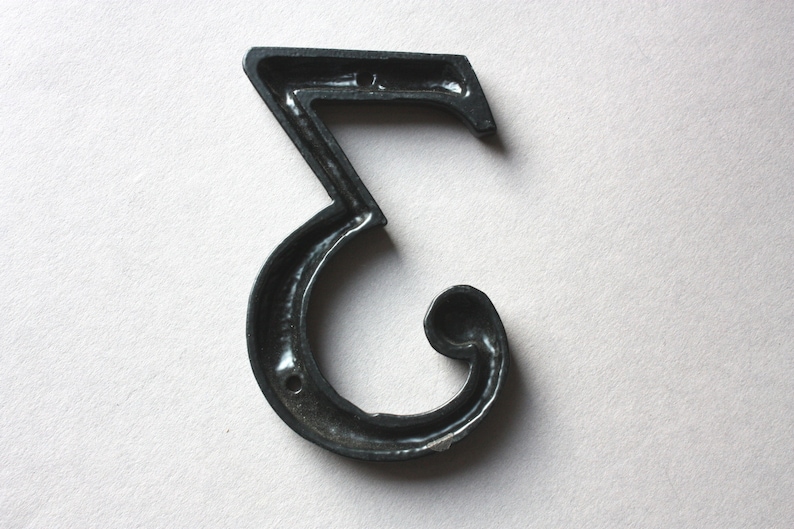 K&ouml;nnte beinhalten: Schwarze Hausnummer drei aus Metall. Die Nummer ist in einer dekorativen, geschwungenen Schriftart gestaltet.