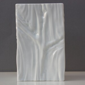 May include: White ceramic vase with a textured, wood-like design.