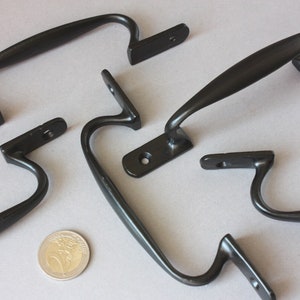 Könnte beinhalten: Fünf schwarze Metall-Türgriffe mit gebogenem Design. Die Griffe sind aus Metall und haben eine schwarze Oberfläche.