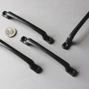 Könnte beinhalten: Vier schwarze Metall-Schranktürgriffe mit einem einfachen, leicht geschwungenen Design.