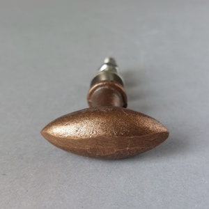以下が含まれることがあります： ブラシ仕上げの銅製の楕円形のキャビネットノブ。ノブには銀色のネジが付いています。