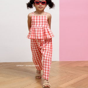 May include: A young child wearing a red and white gingham top and pants set, paired with red sunglasses. The outfit is a matching two-piece set. The image includes the text "HELLO DEAR KIDS" and "#R39".