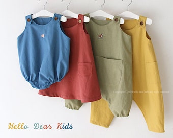 May include: Three different colored linen baby overalls hanging on a wooden rack. The overalls are blue, red, and yellow. The overalls have a pocket on the front and a button closure on the straps. The text "Hello Dear Kids" is at the bottom of the image. The text "#R60" is in the top right corner of the image.