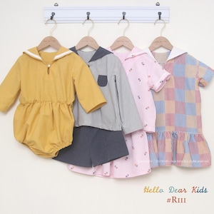 May include: Four children's clothing items hanging on a white rack. The items include a yellow long-sleeved onesie, a striped long-sleeved shirt with a matching pair of dark blue shorts, a pink short-sleeved dress with a floral pattern, and a red and blue plaid short-sleeved dress. The text "Hello Dear Kids #RIII" is at the bottom of the image.