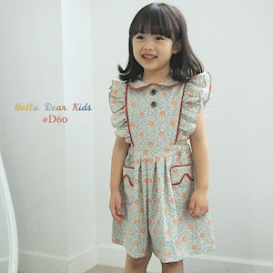 Puede incluir: Una niña pequeña lleva un vestido de flores azul claro y blanco con ribetes rojos y un cuello con volantes. El vestido tiene bolsillos en la parte delantera y cierre de botones. Lleva sandalias beige con pompones. El texto "Hello Dear Kids #D60" es visible en la imagen.