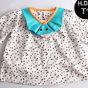 May include: A white dress with black polka dots and a turquoise and orange collar. The collar has a ruffled design.
