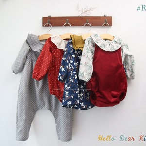 Könnte beinhalten: Vier Baby-Bodys hängen an einem Holzgestell. Die Bodys sind in verschiedenen Farben und Mustern, darunter grau mit weißen Punkten, rot mit weißen Punkten, weiß mit blauem Blumendruck und rot mit weißem Blumendruck. Die Bodys haben Rüschenkragen und lange Ärmel. Der Text "#R53" befindet sich in der oberen rechten Ecke des Bildes. Der Text "Hello Dear Kids" befindet sich in der unteren rechten Ecke des Bildes.