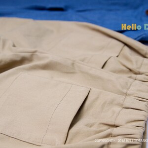 May include: Beige pants with a large pocket on the back and an elastic waistband. The pants are made of a soft, comfortable fabric. The text "Hello Dear Kids #P12" is visible on the image.
