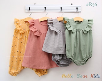 May include: Four baby outfits hanging on a rack. The outfits are a yellow floral romper, a peach ruffled dress, a gray gingham dress with matching bloomers, and a green ruffled romper. The text "Hello Dear Kids" is printed below the outfits.