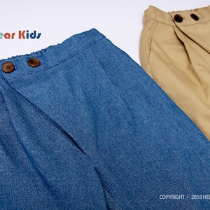 May include: Two pairs of pants, one blue denim and one khaki, both with a wrap-around style and button closures. The denim pants have the text "Hello Dear Kids #P12" on the waistband.