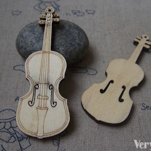 Może przedstawiać: Dwa drewniane wykrojniki w kształcie skrzypiec, jeden z bardziej szczegółowym wzorem, a drugi z prostszym. Oba są nieoszlifowane i gotowe do pomalowania lub ozdobienia.