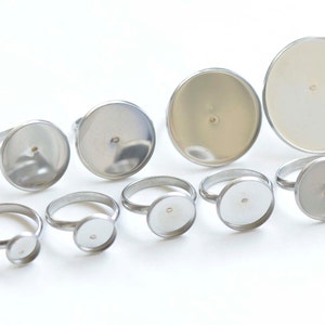 May include: Assortment of silver ring blanks with round bezels of varying sizes. The bezels are smooth and have a slight shine.