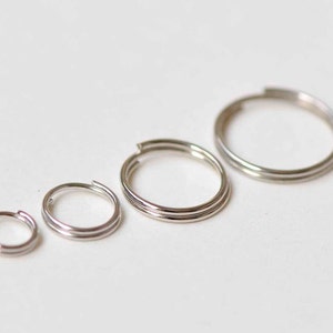 May include: Four silver hoop earrings of different sizes. The earrings are all double-hooped.