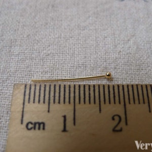 May include: A gold-colored head pin measuring 1 inch in length. The pin has a small round head and is shown next to a ruler.