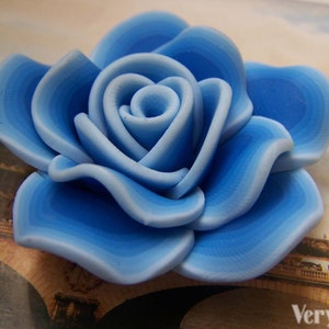 Peut inclure: Une rose en c&eacute;ramique bleue et blanche avec un design en couches. La rose est un accent d&eacute;coratif pour une maison ou un bureau.