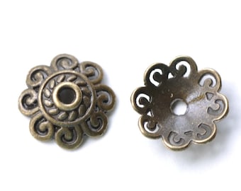 Puede incluir: Dos tapas de cuentas de metal de color dorado antiguo con un diseño floral decorativo. Las tapas tienen un agujero redondo en el centro.