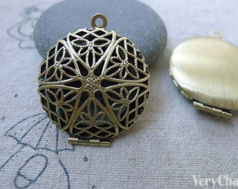 May include: Two antique gold-toned locket pendants. One pendant has a filigree design with a floral pattern. The other pendant is solid and smooth. Both pendants have a hinged closure.