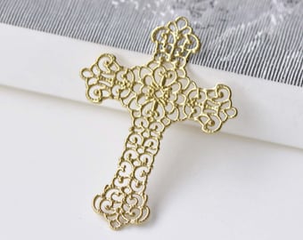 May include: A gold-colored filigree cross with intricate floral and scrollwork designs. The cross is made of metal and has a delicate, openwork pattern. The cross is a religious symbol.