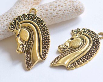 Puede incluir: Dos abalorios de metal dorado en forma de cabeza de caballo con detalles intrincados. Los abalorios tienen una superficie texturizada y un bucle para sujetarlos a joyas u otras manualidades.
