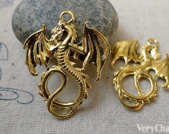 May include: Two gold-colored metal dragon charms with intricate details. The dragons are in a curled position with wings spread out. The charms have a loop at the top for attaching to jewelry or other crafts.