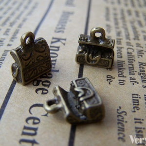May include: Three antique gold-toned metal charms shaped like treasure chests. The charms have intricate details and are perfect for adding a vintage touch to jewelry or crafts.