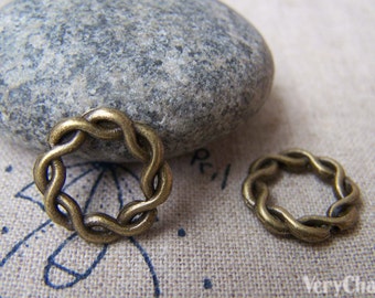 May include: Two antique gold-toned metal rings with a braided design. The rings are on a light brown fabric surface.