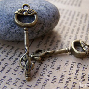 May include: Two antique gold-toned skeleton keys with ornate designs. The keys have a floral motif and are connected to each other.