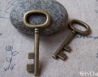 May include: Two antique-style brass keys with intricate details. The keys are on a textured fabric background.