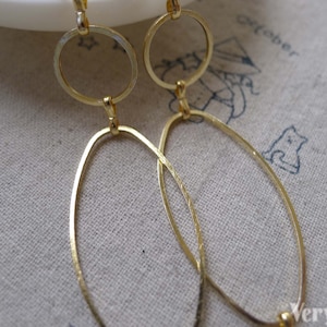 May include: A pair of gold-toned dangle earrings with two oval shapes and a smaller circle on each earring.