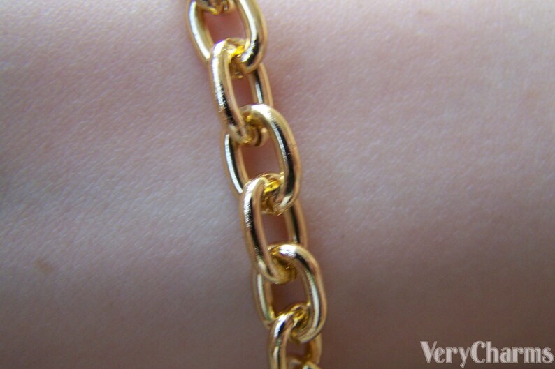 May include: A close-up of a gold chain necklace with a curb link style. The chain is smooth and shiny.