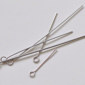 Puede incluir: Un conjunto de cinco alfileres de cabeza plateados con bucles. Los alfileres de cabeza se utilizan para la fabricación de joyas y la artesanía.