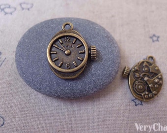 May include: Two antique bronze charms, one shaped like a clock face with Roman numerals and the other with a detailed gear mechanism.