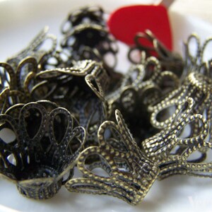 May include: A pile of antique gold metal decorative end caps with a scalloped design. The end caps are made of a delicate, intricate metalwork.