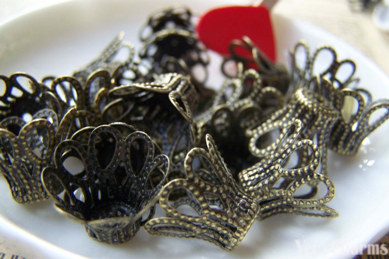 May include: A pile of antique gold metal decorative end caps with a scalloped design. The end caps are made of a delicate, intricate metalwork.