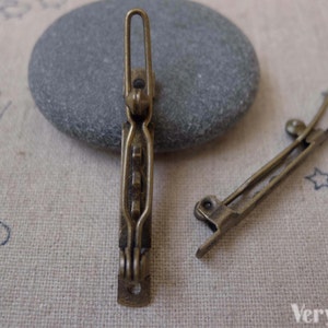 Puede incluir: Dos pinzas para el pelo de metal dorado antiguo. Las pinzas miden aproximadamente 5 cm de largo y tienen un diseño sencillo.