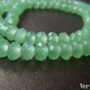 May include: A strand of light green faceted glass beads. The beads are round and have a frosted finish.